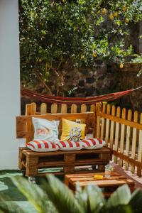 - un banc en bois avec des oreillers à côté d'une table dans l'établissement Lemon Tree Rooms, à Ischia