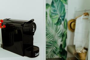 a black coffee maker with a red flower on it at Lemon Tree Rooms in Barano d'Ischia
