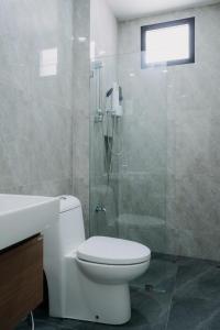 La salle de bains est pourvue de toilettes et d'une douche en verre. dans l'établissement AKIRA Villa, à Buriram