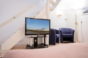 a living room with a tv and a staircase at Haus-Wattblick-Appartement-M-W-U in Braderup