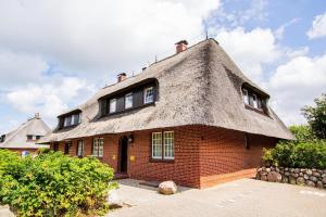 a large brick house with a thatched roof at Haus-Wattblick-Appartement-M-W-U in Braderup