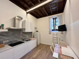 Appartamento La Corte في أوليدجو: مطبخ مع دواليب بيضاء وطاولة مع كراسي