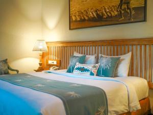 a bedroom with a large bed with blue and white pillows at New Pondok Sara Villas - CHSE Certified in Seminyak