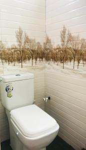 - des toilettes blanches dans une salle de bains avec une photo d'arbres dans l'établissement Villa Moon breeze Nilaveli, à Trincomalee