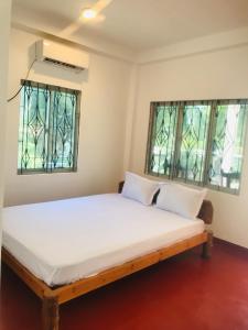 a bed in a room with two windows at Villa Moon breeze Nilaveli in Trincomalee