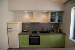 een keuken met groene kasten en een witte koelkast bij VUAR SUITES in Petalidhion