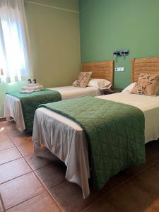 um quarto com três camas com lençóis verdes e brancos em HOSTAL TREVELEZ em El Ejido