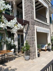 d'une terrasse avec une table, des chaises et des fleurs blanches. dans l'établissement Lustica Bay Marina Studio****, à Radovići