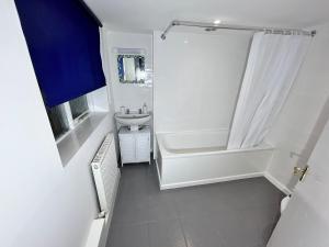 Down Ampney cottage في Down Ampney: حمام أبيض مع دش ومغسلة