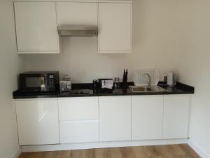 a white kitchen with white cabinets and a sink at theoldgarage in Chichester