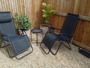 trois chaises noires et une table devant une clôture dans l'établissement theoldgarage, à Chichester