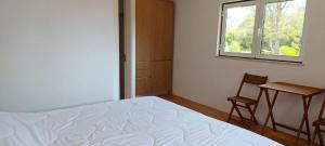 1 dormitorio con cama, ventana y silla en Casas da Barra en Praia de Mira