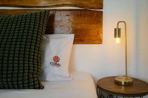 Cama con almohada y mesa con lámpara en Coral Boutique Suites en Albufeira