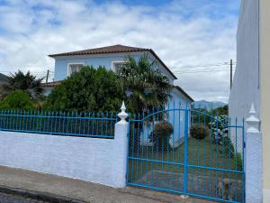 una cerca azul frente a una casa blanca en Quinta das rãs, en Ponta Delgada