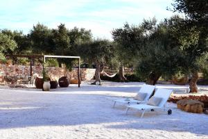 - deux chaises blanches assises dans le sable dans l'établissement Trulli di Titti - Country House, à Castellana Grotte