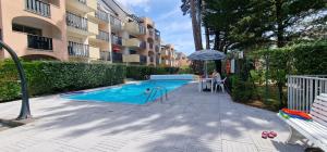 een zwembad met een parasol naast een gebouw bij HOME ET HOLIDAY Le Chardonnay in La Baule