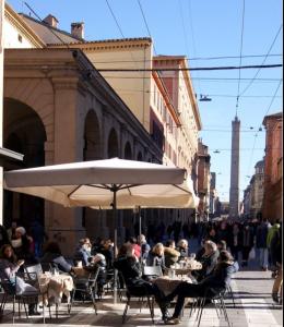 a group of people sitting at tables under an umbrella at Casa Nina Bologna Centro in Bologna