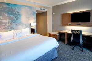 a hotel room with a bed and a desk and a television at Courtyard by Marriott Muncie at Horizon Convention Center in Muncie
