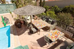 - une terrasse avec 2 tables et un parasol à côté de la piscine dans l'établissement Riad Swaka, à Marrakech