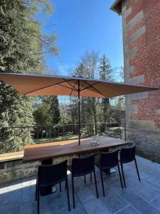 una mesa con sillas y una sombrilla en el patio en Holiday house for design lovers! en Chimay