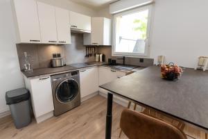 a kitchen with a washing machine and a table at Le splend'id à 10min de Disneyland in Chessy