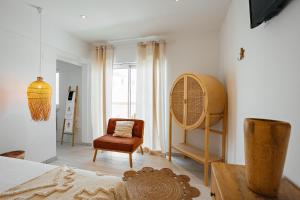 een slaapkamer met een bed, een stoel en een raam bij Coral Boutique Suites in Albufeira