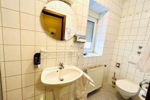 a bathroom with a sink and a toilet and a mirror at Adler Hotel Garni in Ostfildern