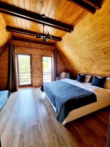 sypialnia z dużym łóżkiem i drewnianymi ścianami w obiekcie Twin Cabins / Cabanele Gemene w Suczawie