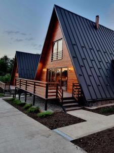 una casa con techo negro y bancos delante de ella en Twin Cabins / Cabanele Gemene, en Suceava