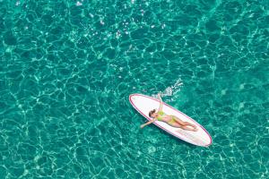 a woman laying on a surfboard in the water at Cormoran Residence in Villasimius
