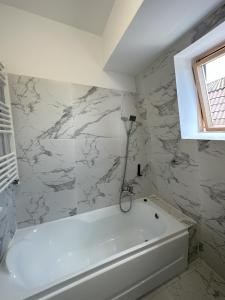 a white bath tub in a bathroom with marble walls at elisio - Maple House in Ghimbav