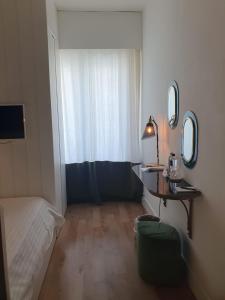 Habitación pequeña con cama, mesa y espejo. en Hotel Ril, en Lido di Jesolo