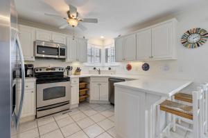 a kitchen with white cabinets and a ceiling fan at 3-level townhome w/ private pool & close to beach! in South Padre Island