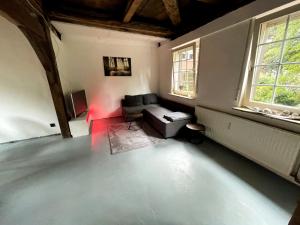 uma sala de estar com um sofá e duas janelas em Fachwerkhaus in Alfhausen 