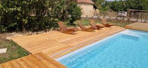una fila de sillas sentadas en una terraza de madera junto a una piscina en COCON en La Douze