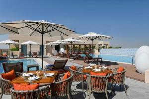 a patio with tables and chairs and a pool at Le Mirage Downtown in Doha