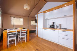 a kitchen and dining room with white cabinets and a table at Prima insula glamping in Brusići