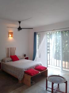 a bedroom with a bed with red pillows and a window at NEW MORINGA in Las Terrenas