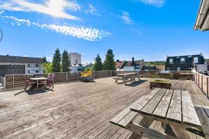 una terraza de madera con bancos y mesas. en Ny sentral og moderne leilighet en Kristiansand