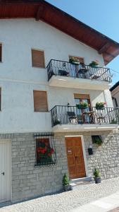un edificio blanco con 2 balcones, mesas y flores en Chez Carlo, en Aosta