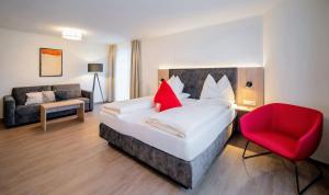 um quarto com uma cama e uma cadeira vermelha em Hotel Rosenvilla em Salzburgo