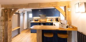 cocina con armarios azules y encimera de madera en Cotswold cottage with hot tub en Bledington