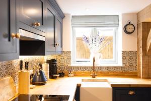 a kitchen with a sink and a window at Cotswold cottage with hot tub in Bledington