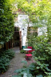 a table and two red chairs in a garden at Carriage House in quiet ecological garden in Antwerp