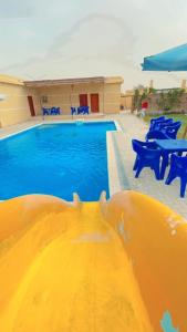 uma grande piscina com cadeiras azuis e uma piscina em تيوليب فيلا em Cidade 6 de Outubro