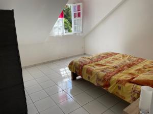 um quarto com uma cama e uma janela em ti sable appartement à 5 minutes de la mer em Saint-Joseph
