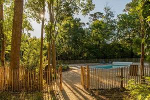 una valla de madera alrededor de una piscina con árboles en Les gîtes des troubadours, en Pennautier