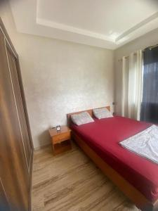 een slaapkamer met een rood bed en een houten vloer bij Élégant & Cosy Appartement in Casablanca