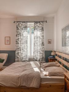 a bedroom with a bed and a window with curtains at La Maison du Markstein in Linthal