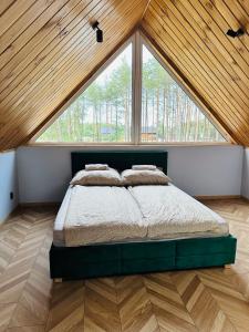 a bedroom with a bed with a large window at Bliżej Lasu in Śliwice